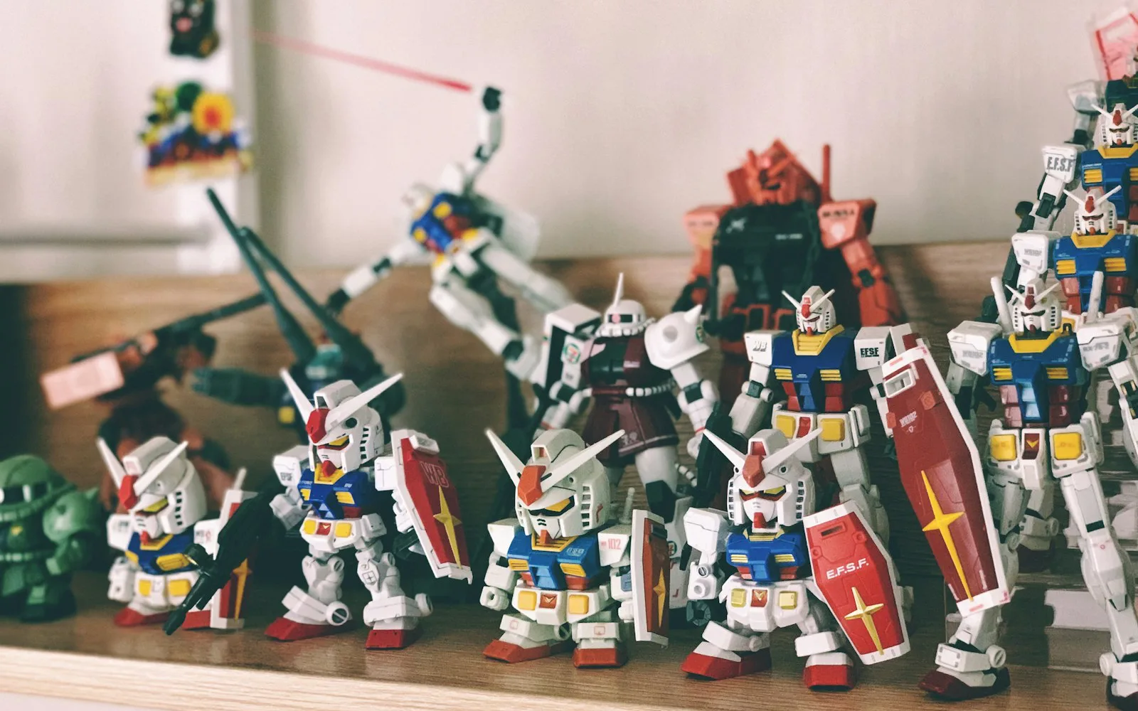 Figurines Gunpla de différentes tailles alignées sur une étagère en bois