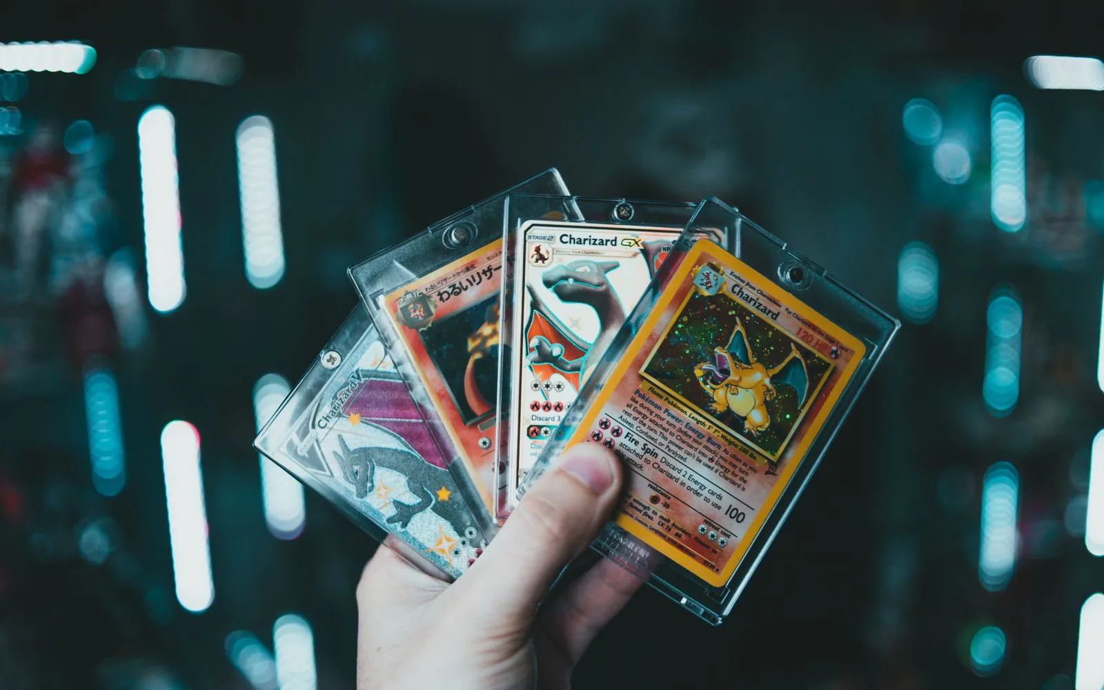 Main tenant plusieurs cartes Pokémon rares dans des étuis rigides